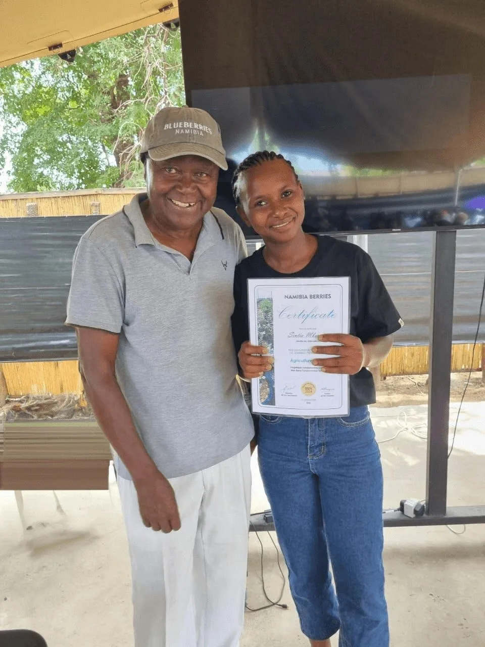 A team member proudly shows her training certificate beside a colleague